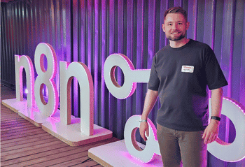 flowio founder Malcolm Gibb at an n8n event, beside the n8n logo installation
